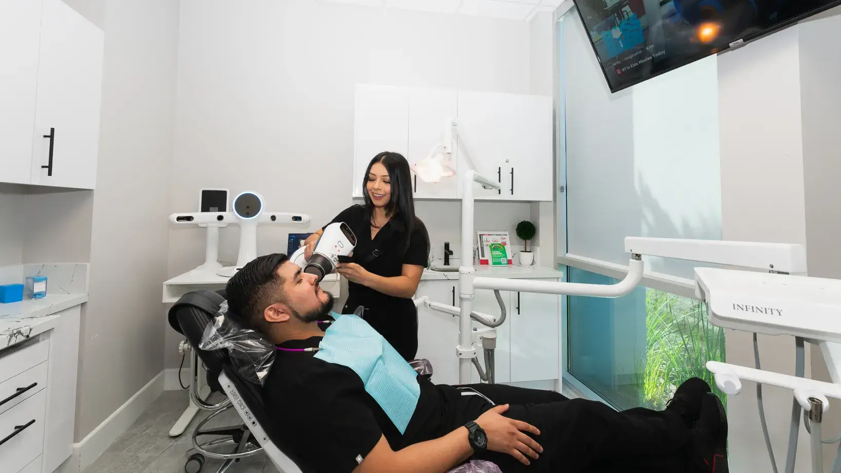 A man in a dentist chair getting his teeth brushed.