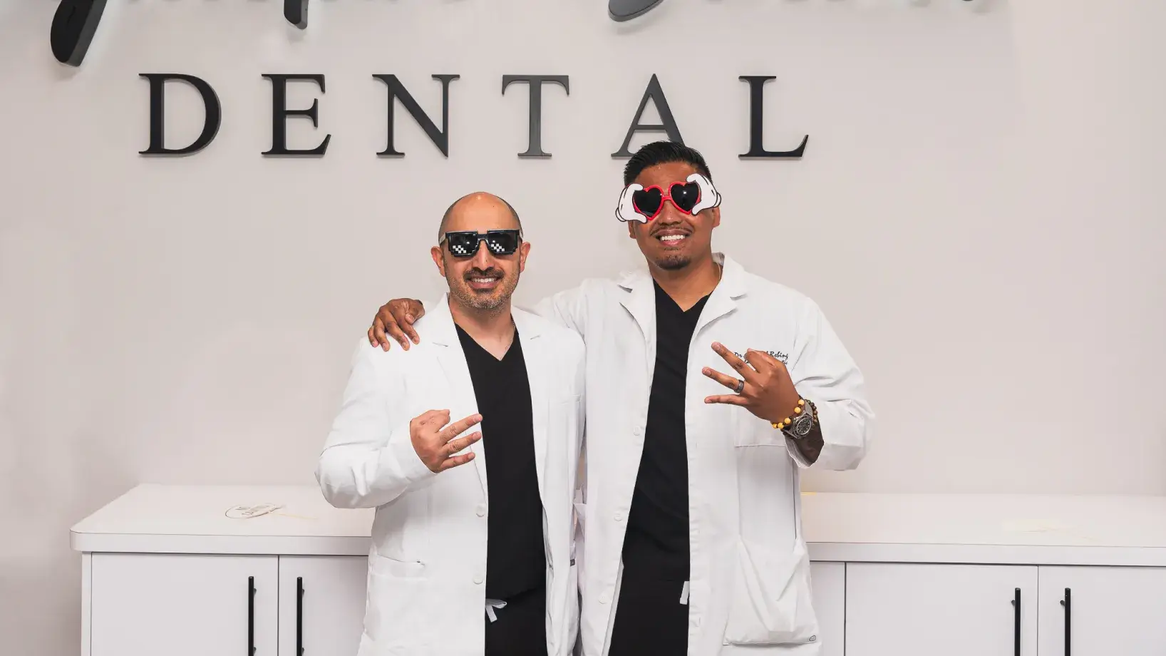 Two men standing next to each other in front of a dental sign.