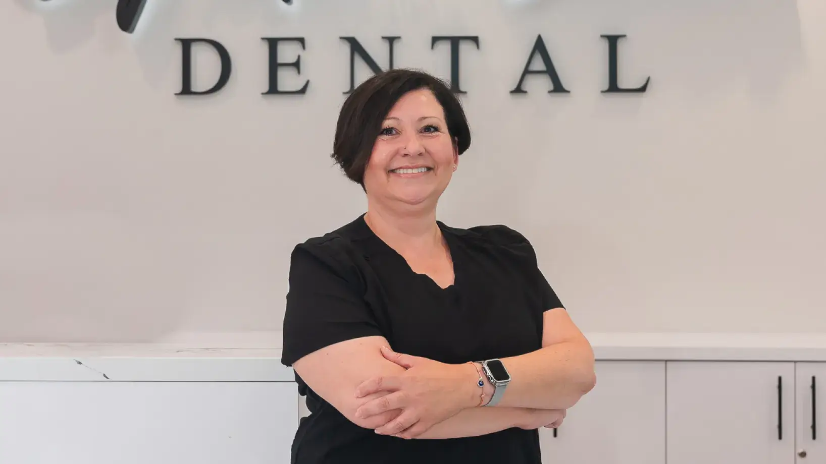 A woman standing in front of a dental sign.