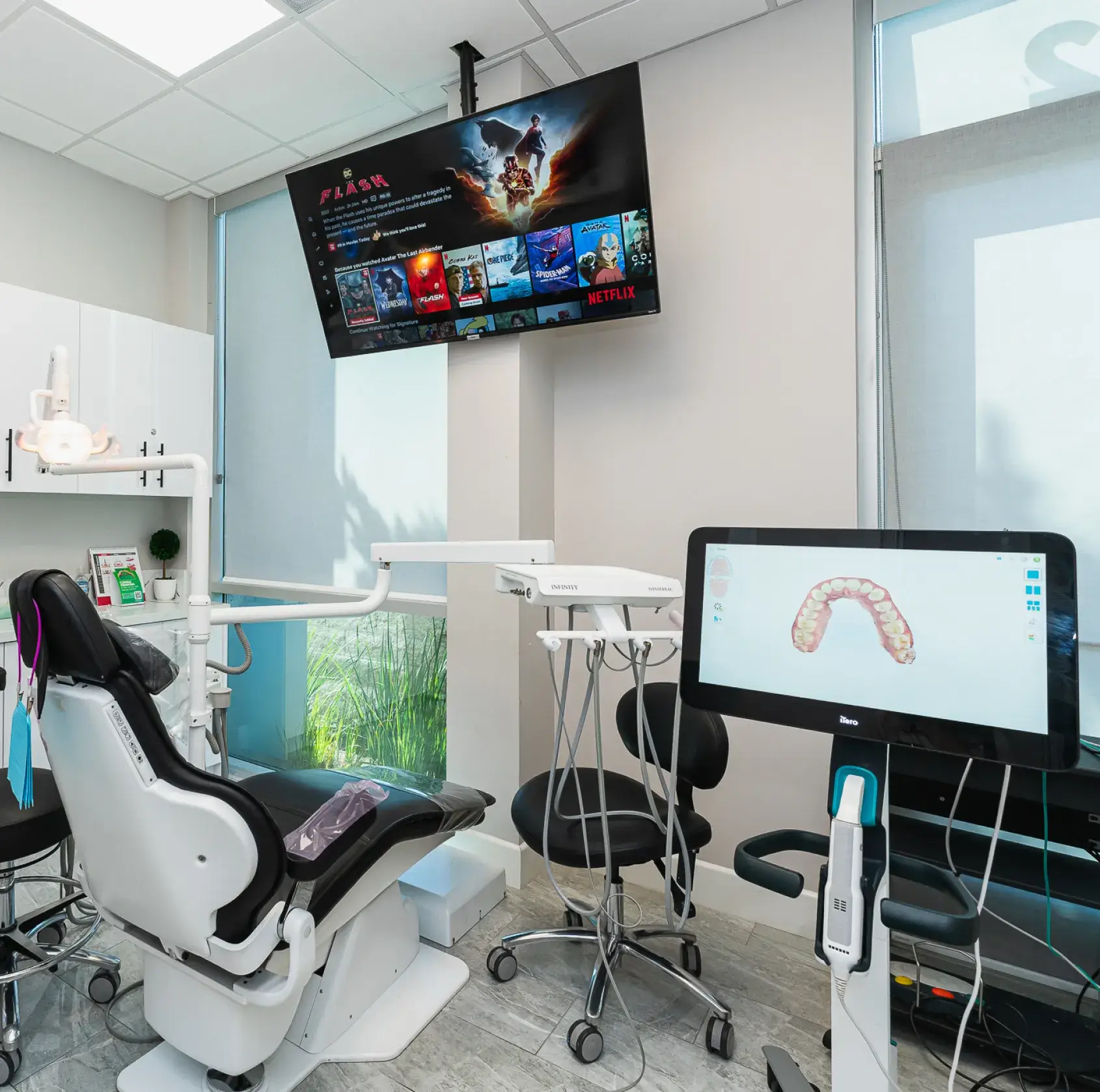 A dental office with a monitor and a chair.