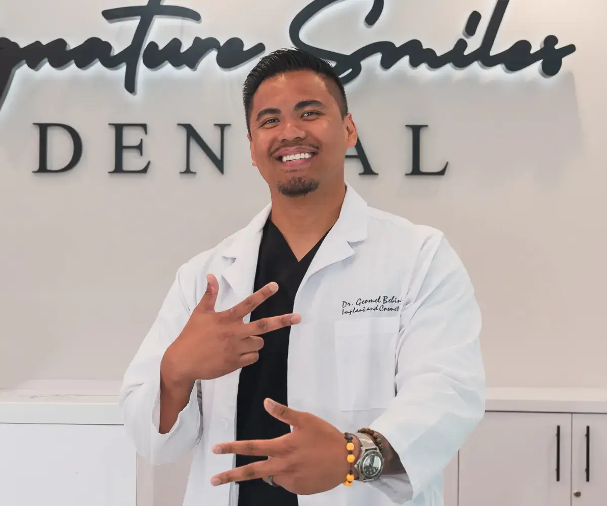 A man in a white lab coat pointing at the camera.