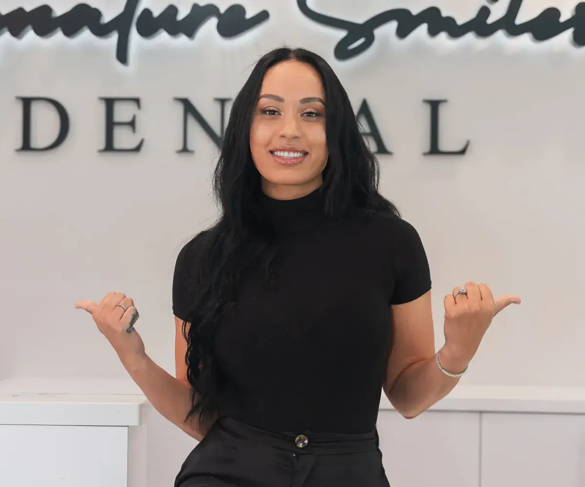 A woman standing in front of a sign.