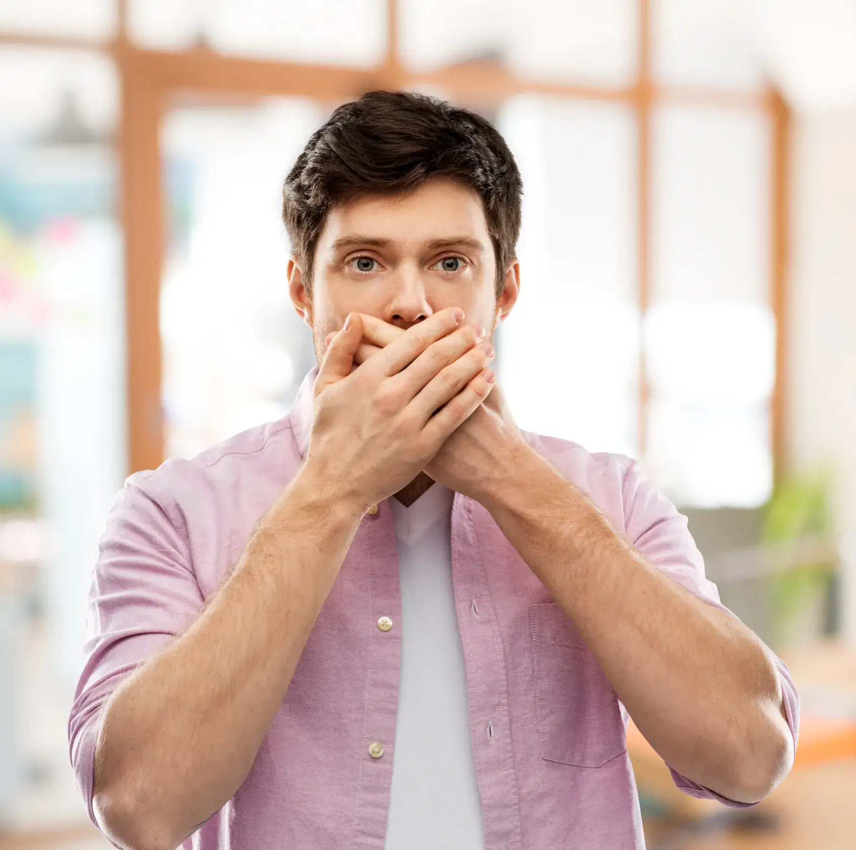 A man covers his mouth with his hands.