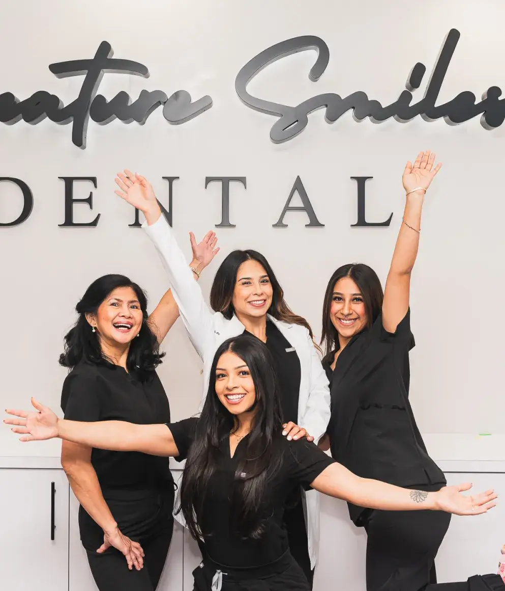 A group of women standing in front of a dental sign.