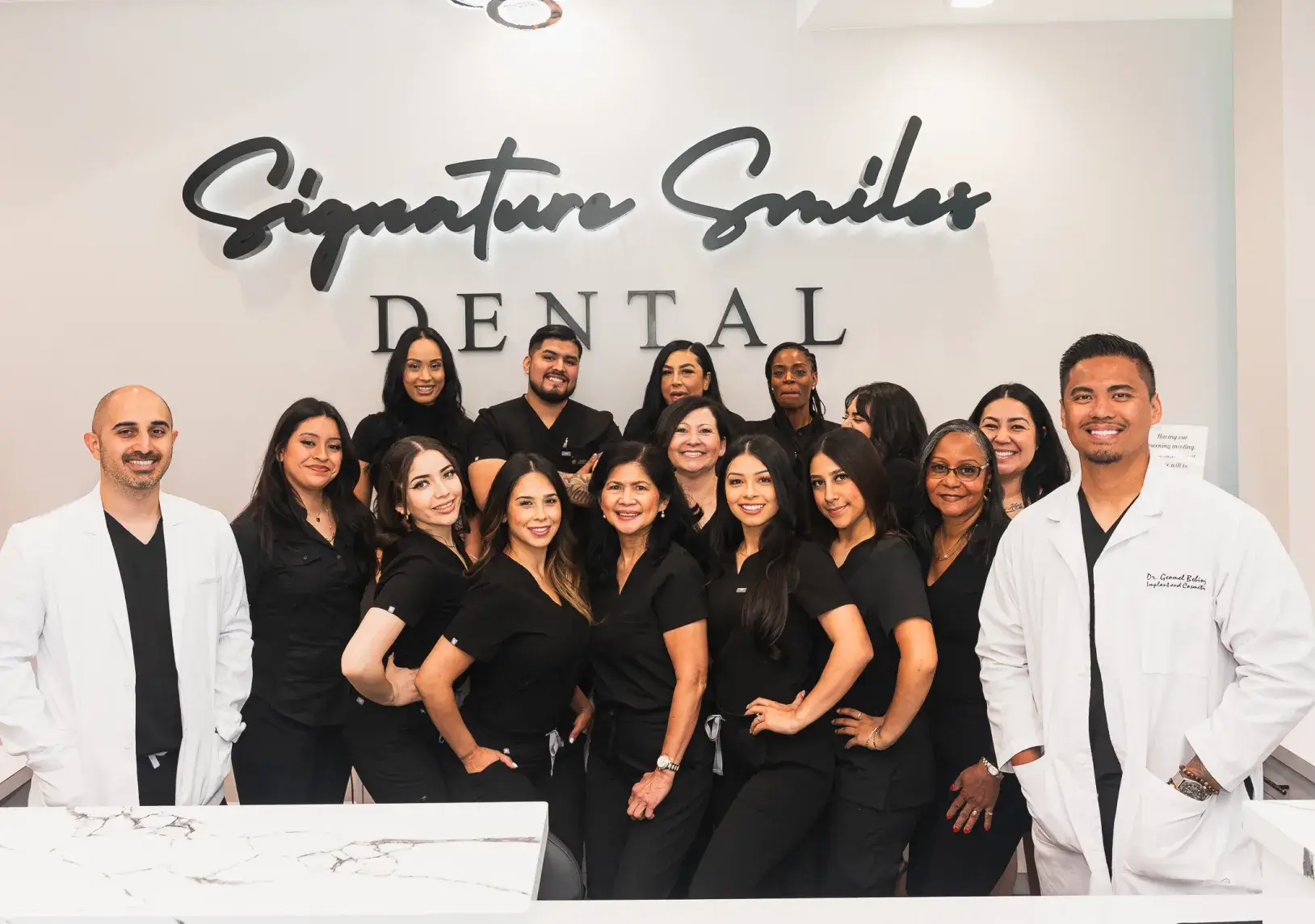 A group of dentists posing in front of a dental office sign.