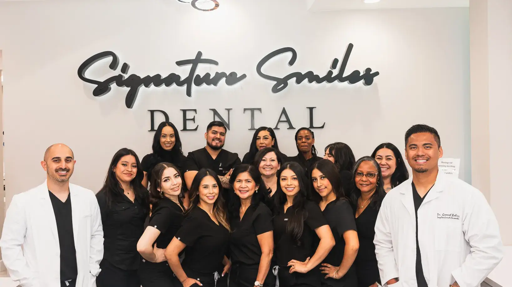 A group of dentists standing in front of a dental office sign.