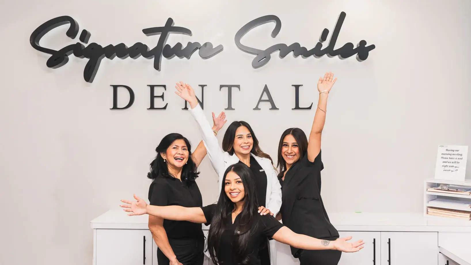 A group of women standing in front of a dental sign.