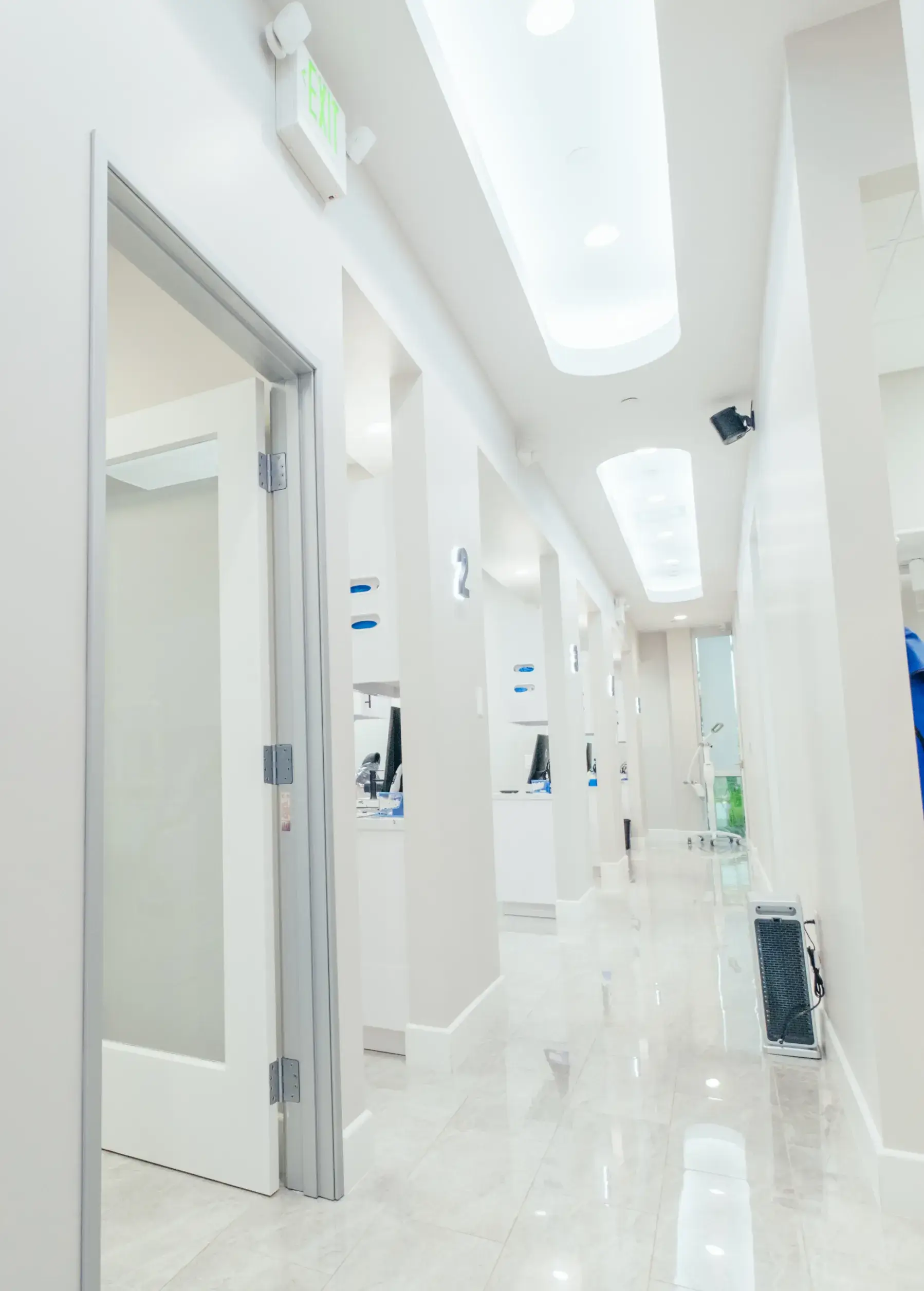 A long hallway with a white tiled floor and white walls.