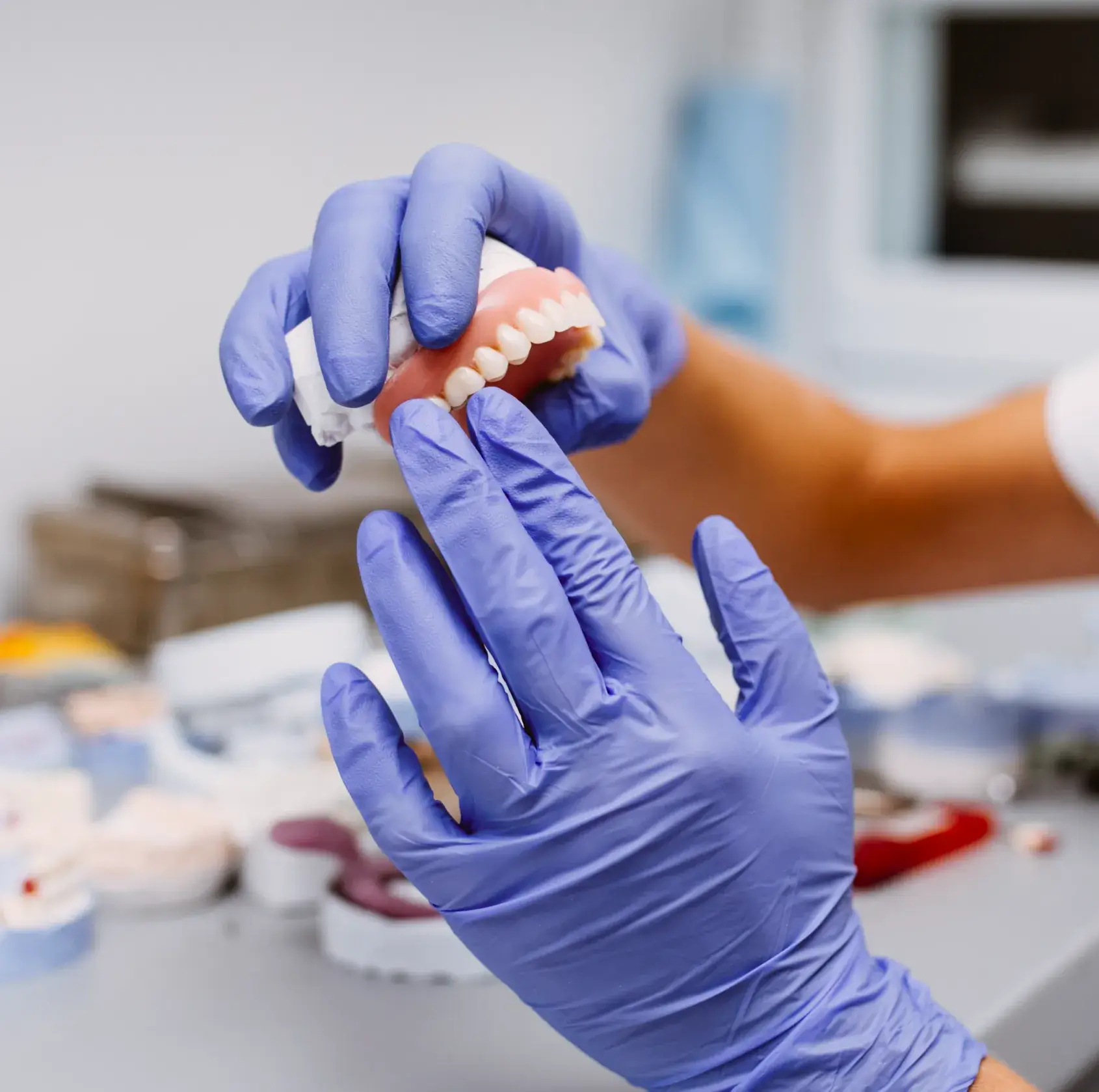 A person in blue gloves holding a toothbrush.