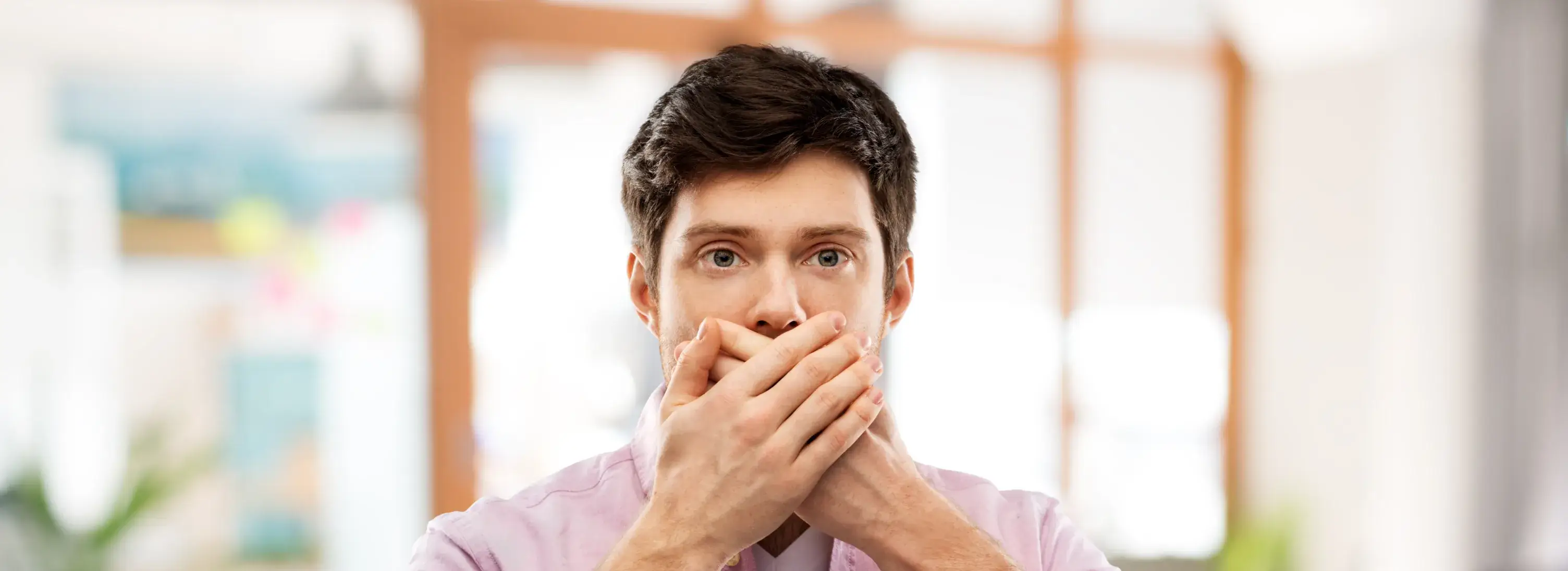 A man covers his mouth with his hands.