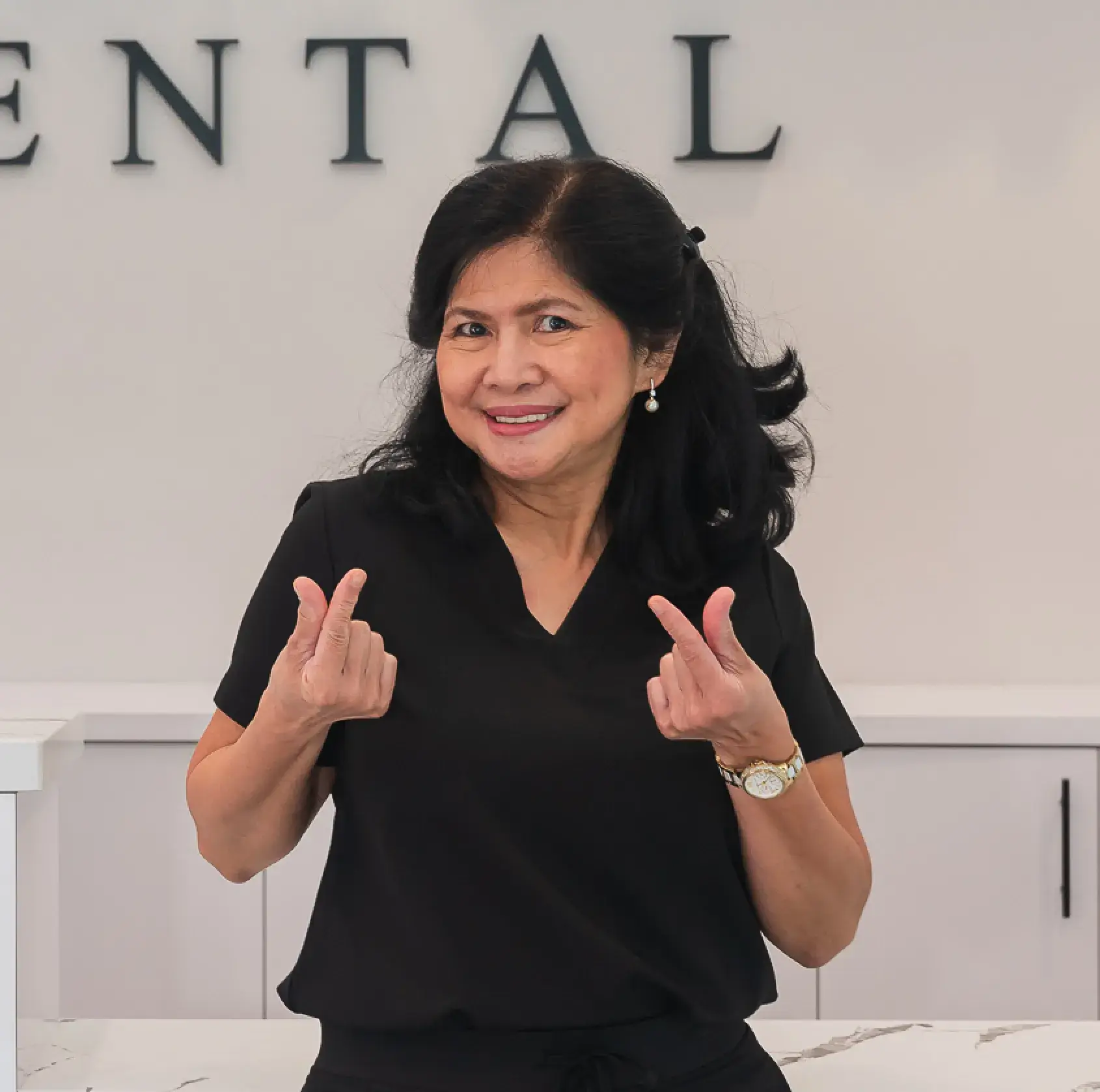 A woman standing in front of a sign giving the peace sign.