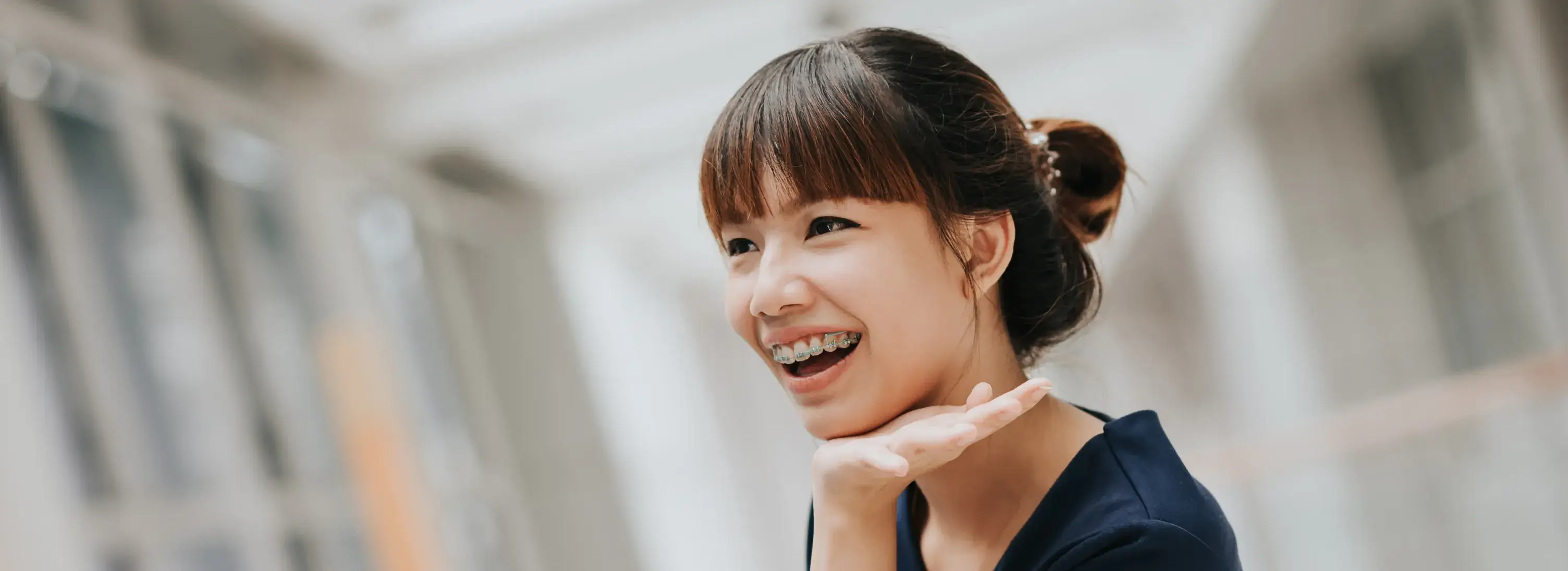 A woman with a ponytail smiling and pointing to the side.