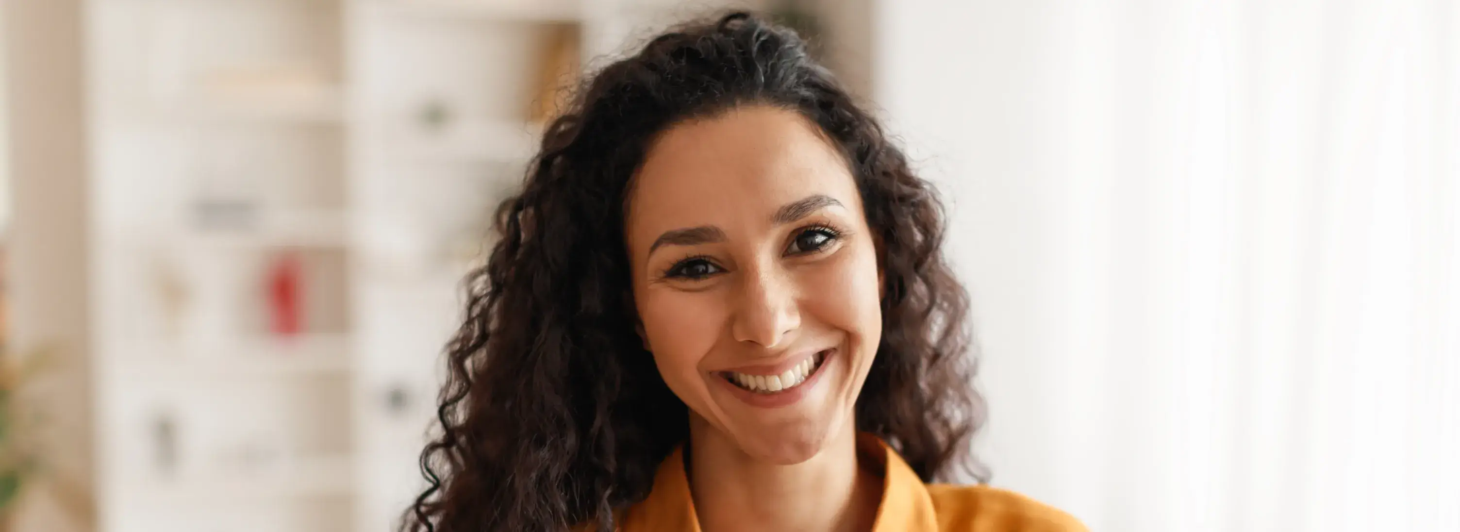 A woman with curly hair smiling at the camera.