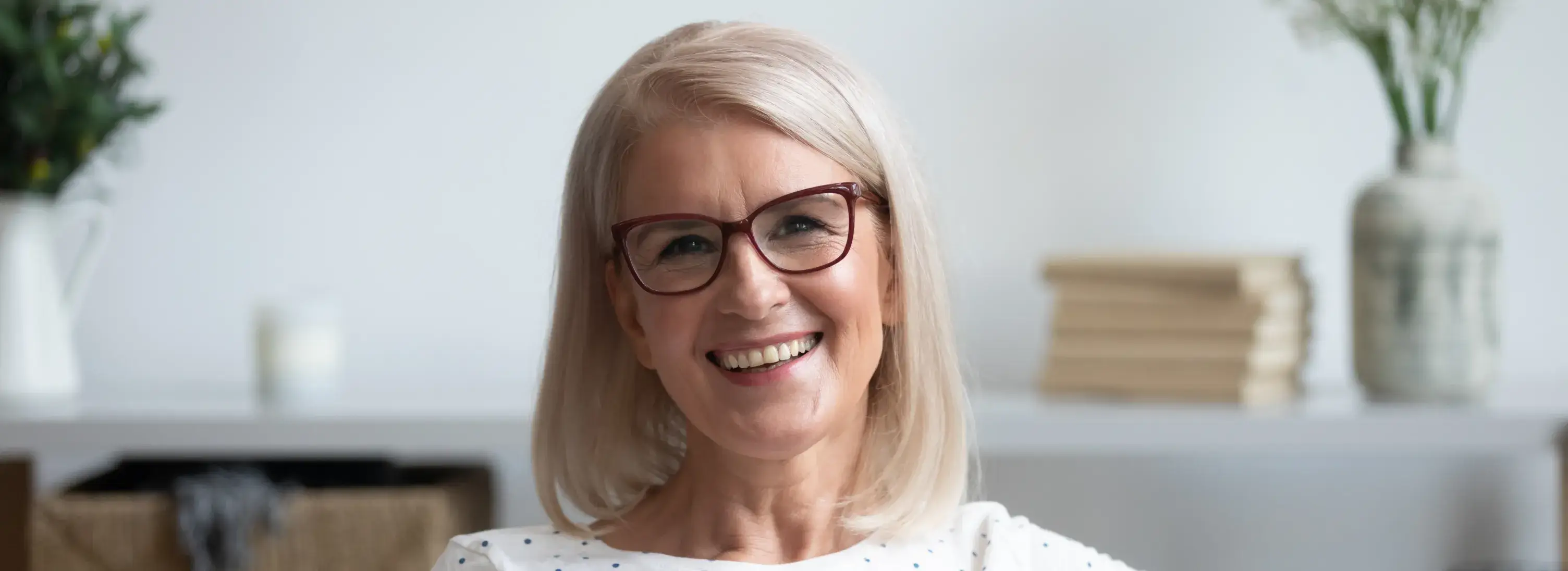 An older woman with glasses smiling for the camera.