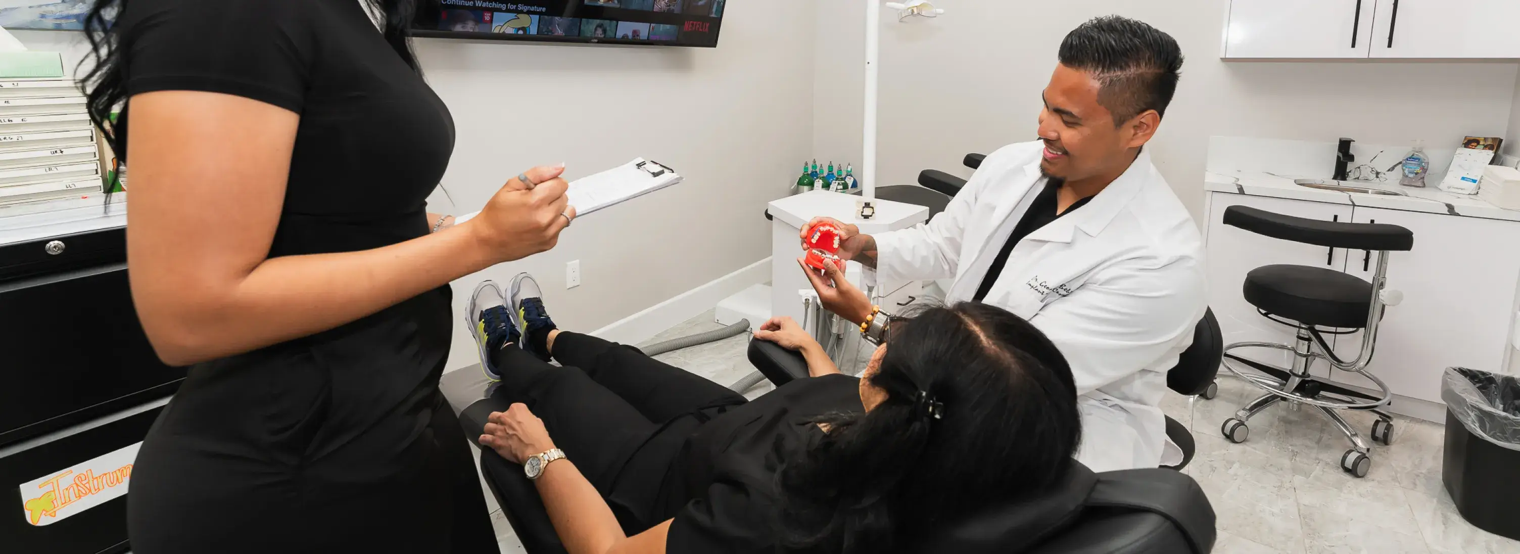 A man in a dentist's office getting his teeth brushed.