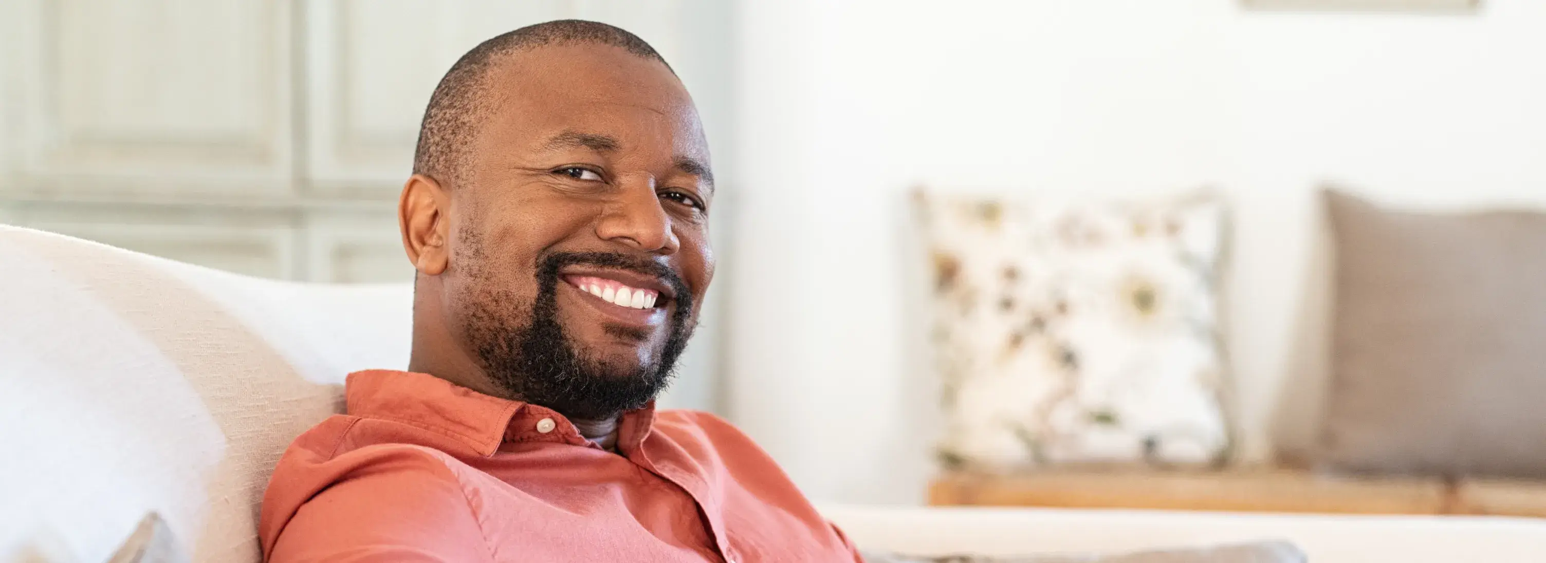 A man sitting on a couch smiling at the camera.