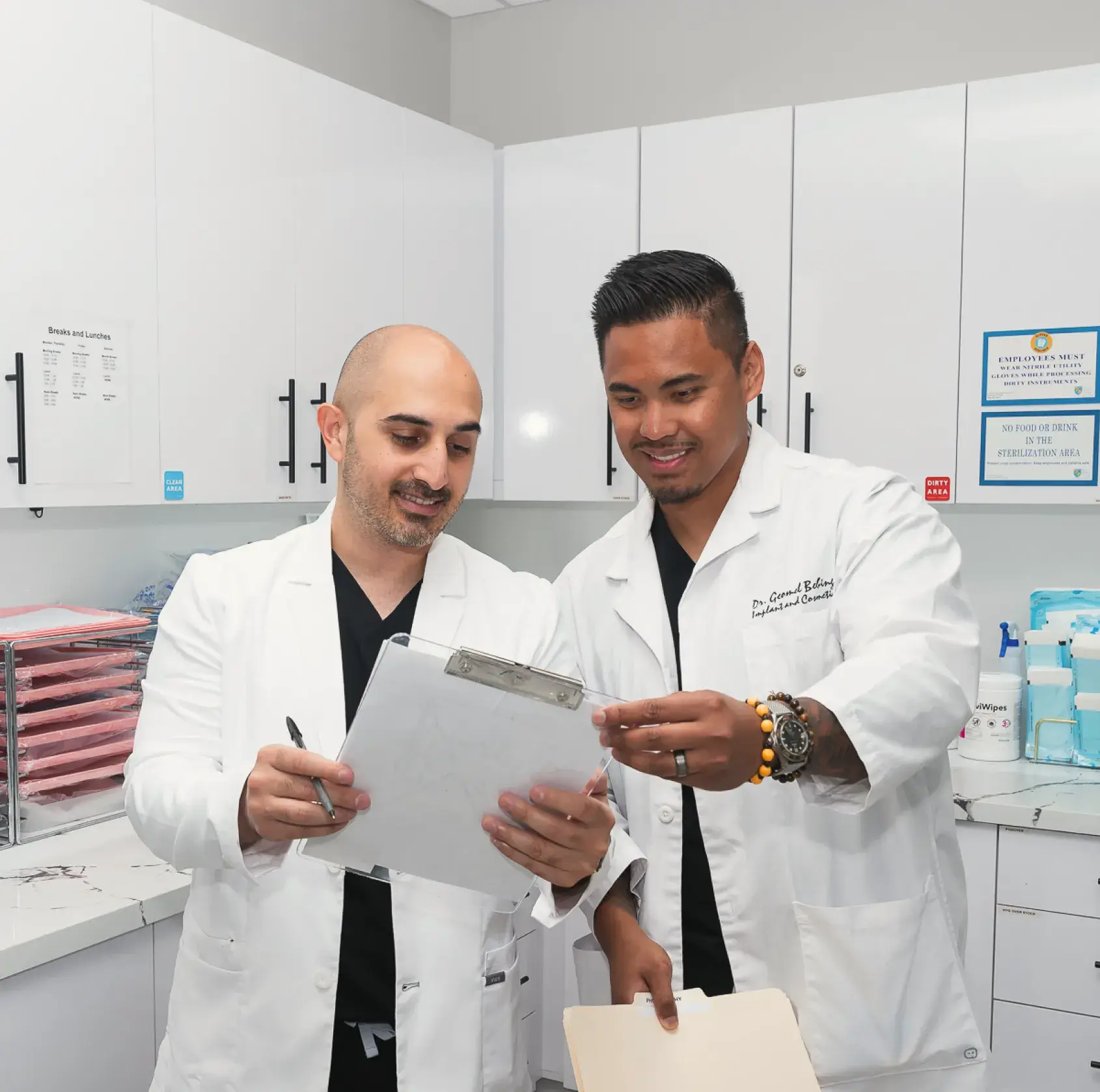 Two men in lab coats looking at a piece of paper.