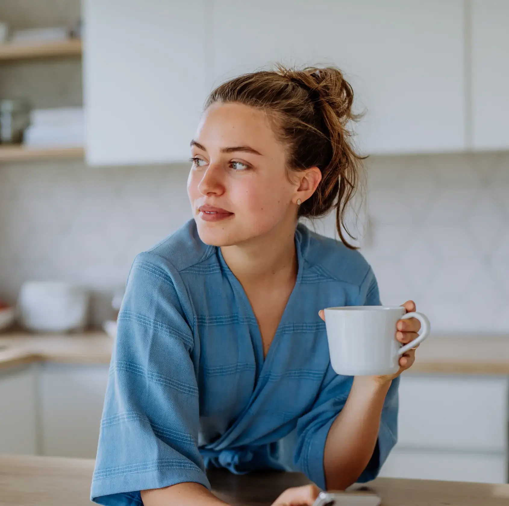A woman sitting at a table with a cup of coffee.