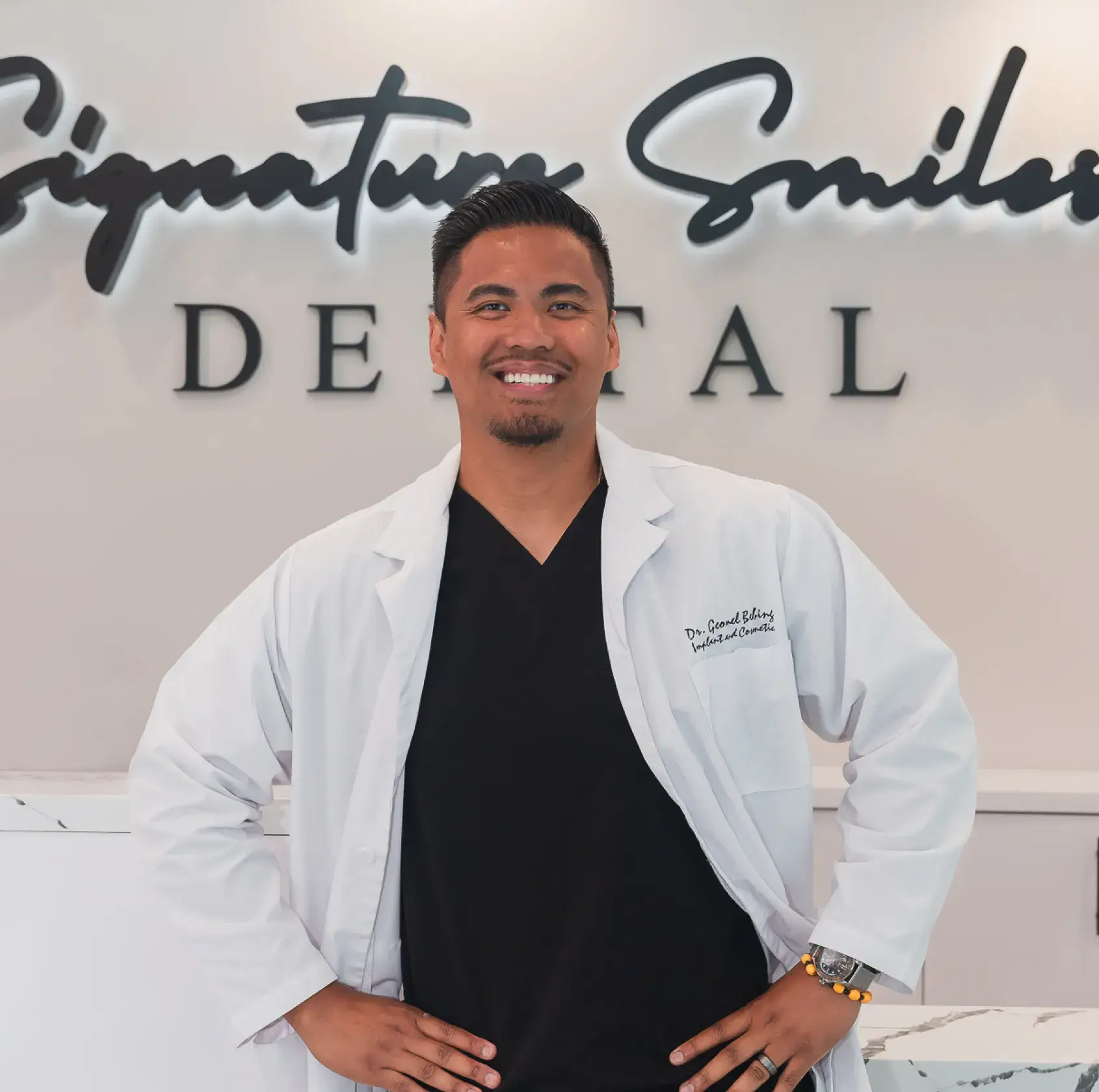 A man in a white lab coat standing in front of a sign.