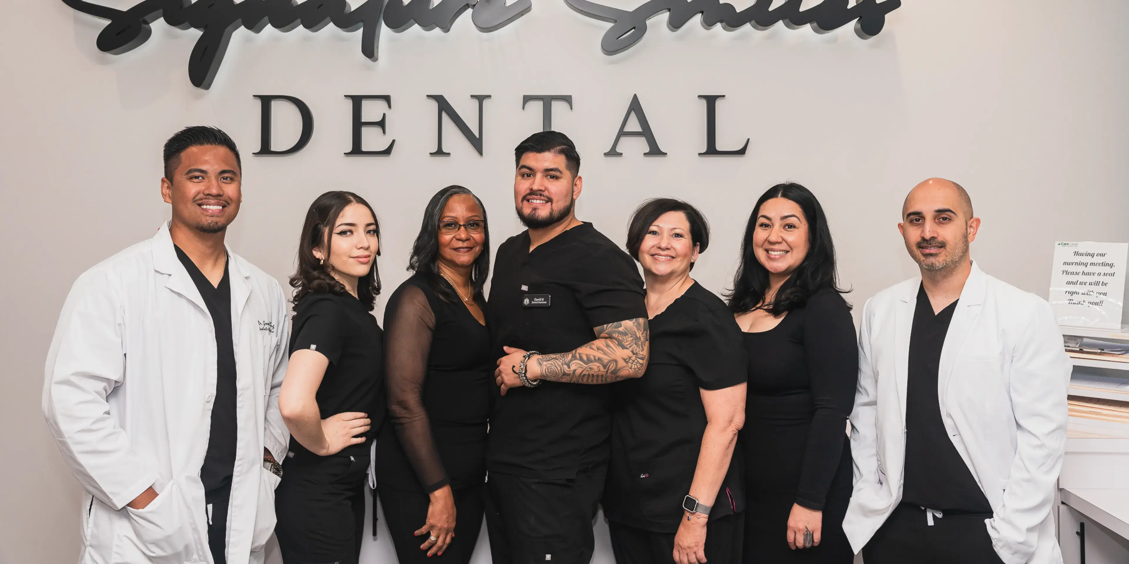 A group of dentists standing in front of a dental office sign.