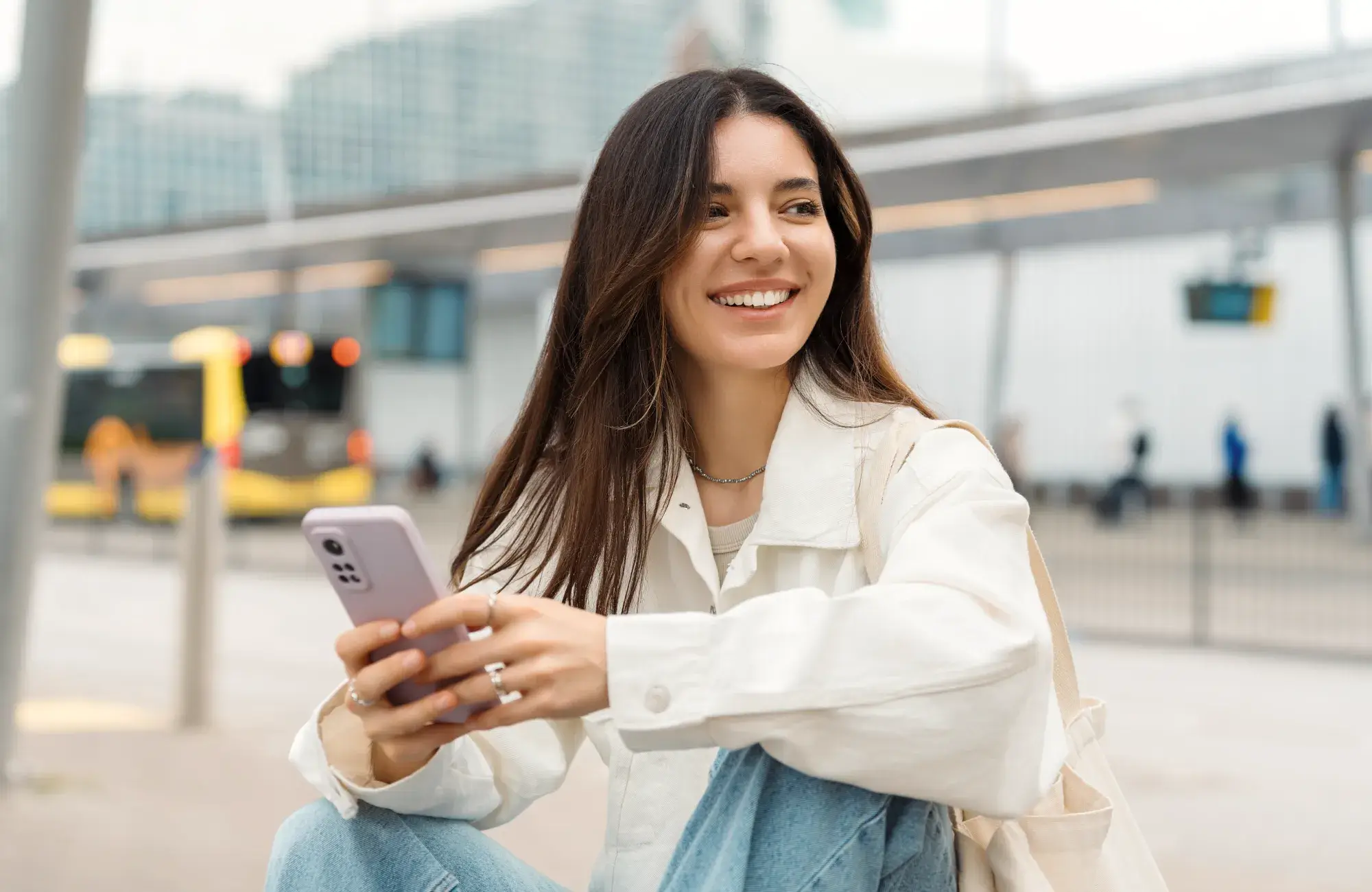 A woman sitting on the ground holding a cell phone.