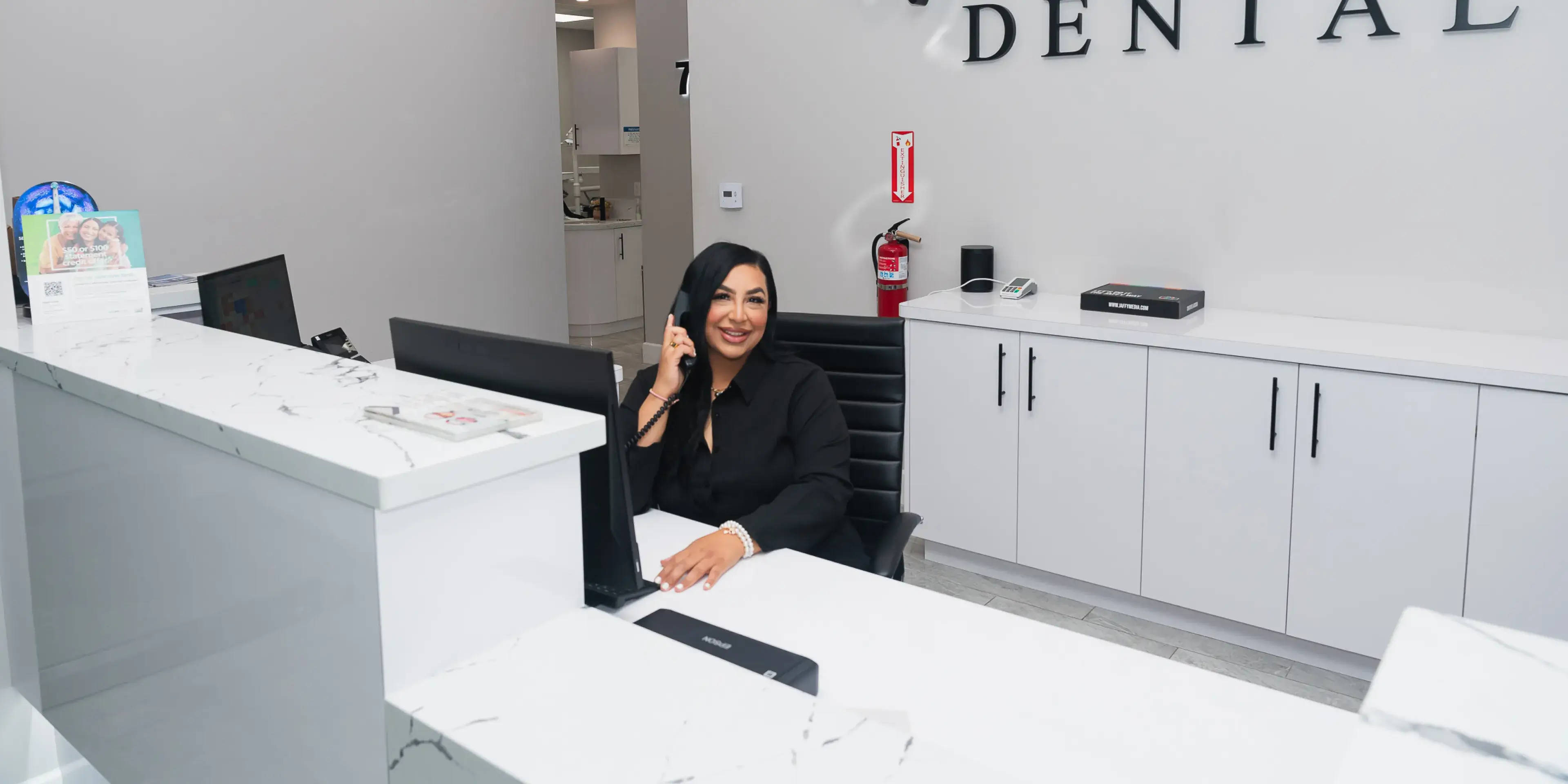 A woman sitting at a desk in a dental office.
