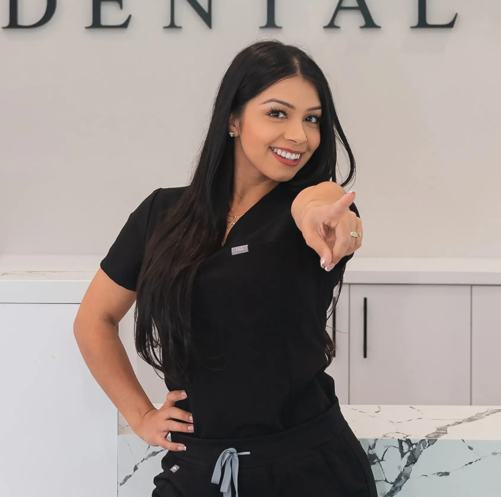 A woman pointing at the camera with a smile on her face.