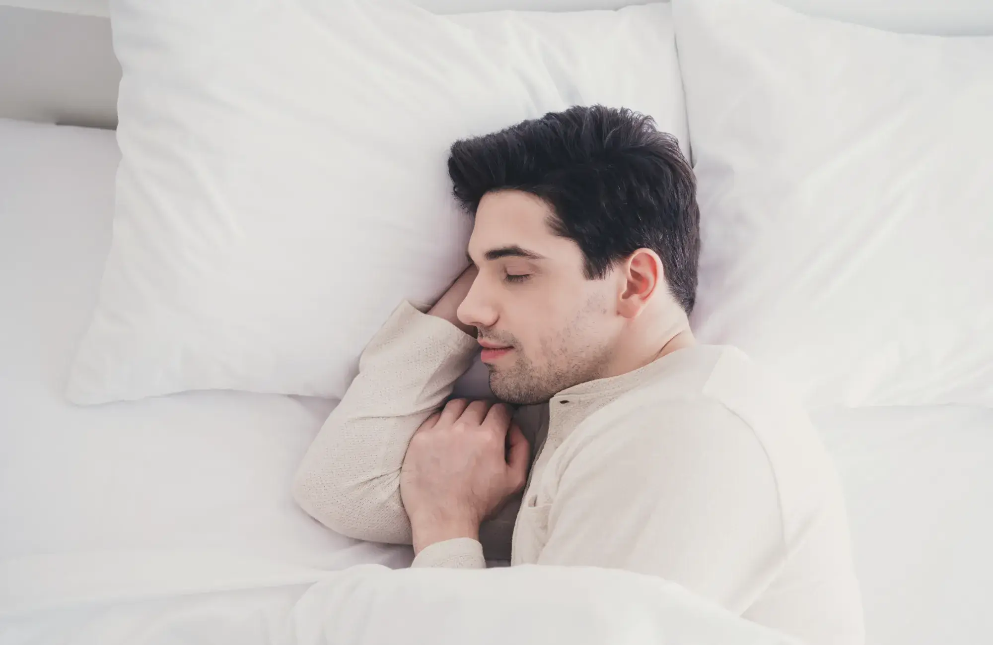 A man laying in bed with his head on his pillow.