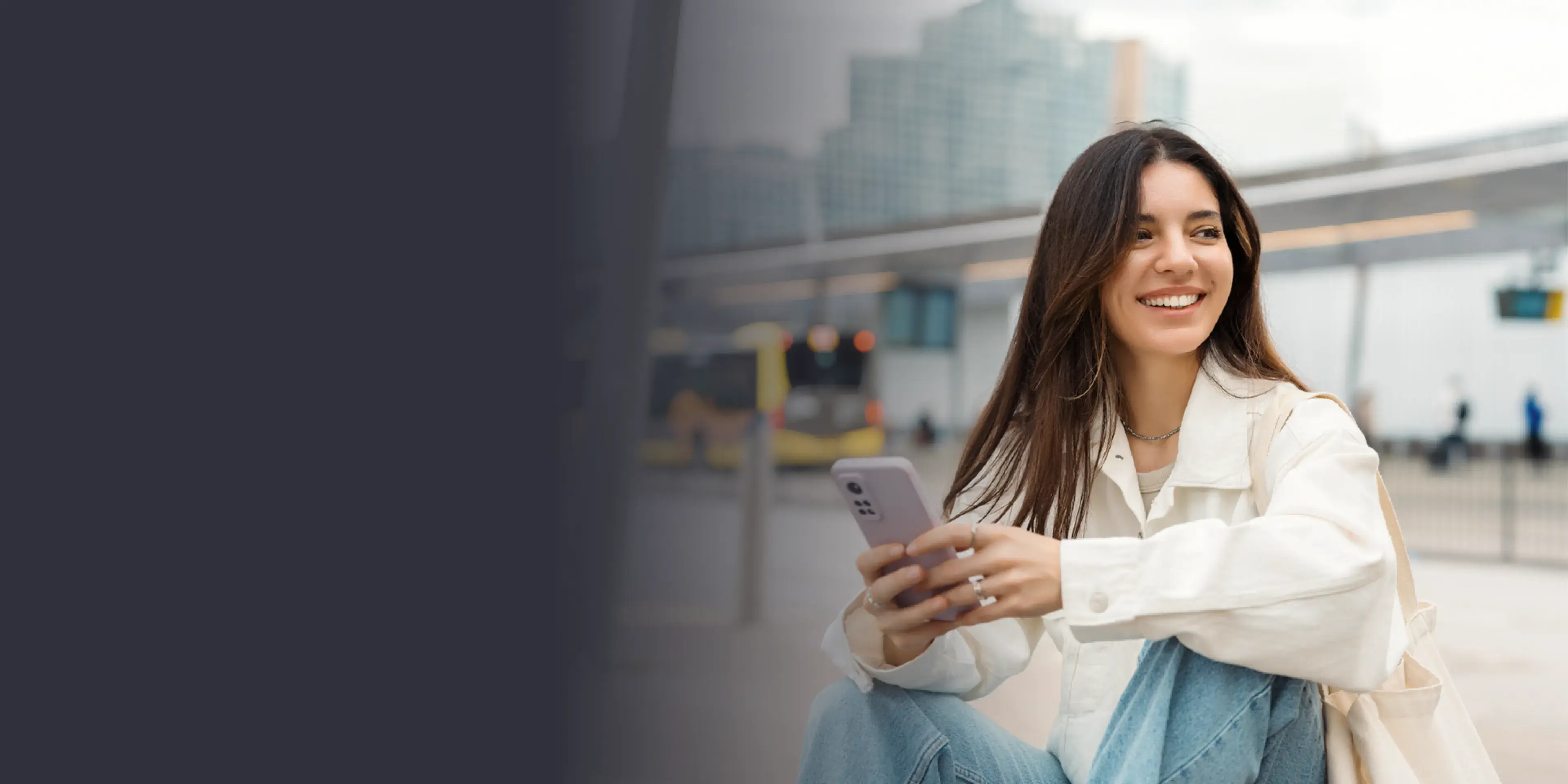 A woman sitting on the ground looking at her cell phone.