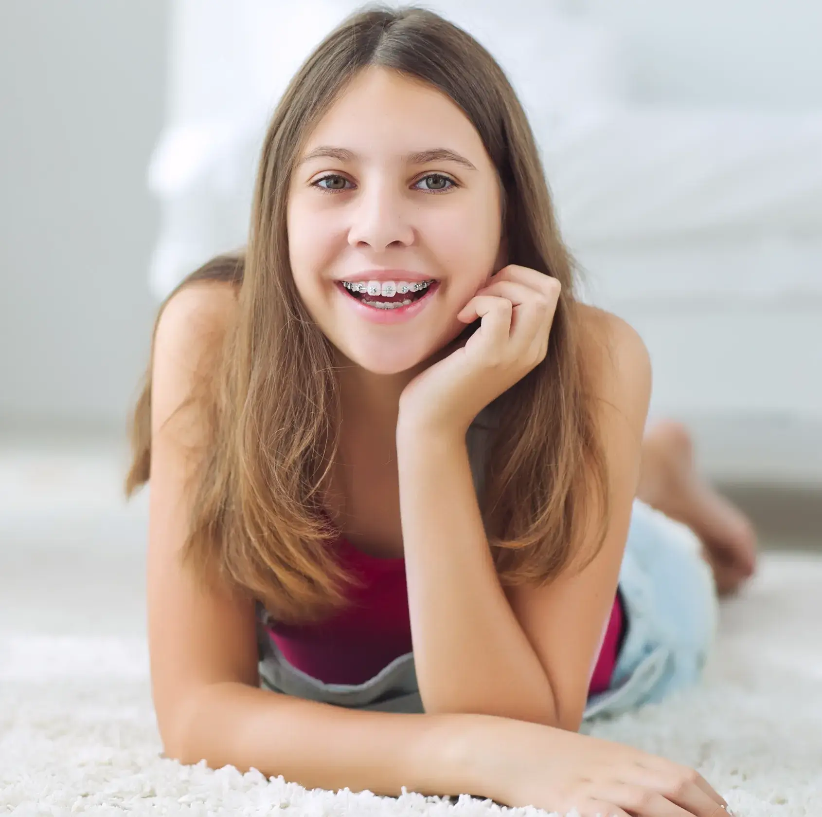 A woman laying on the floor with her hand on her chin.