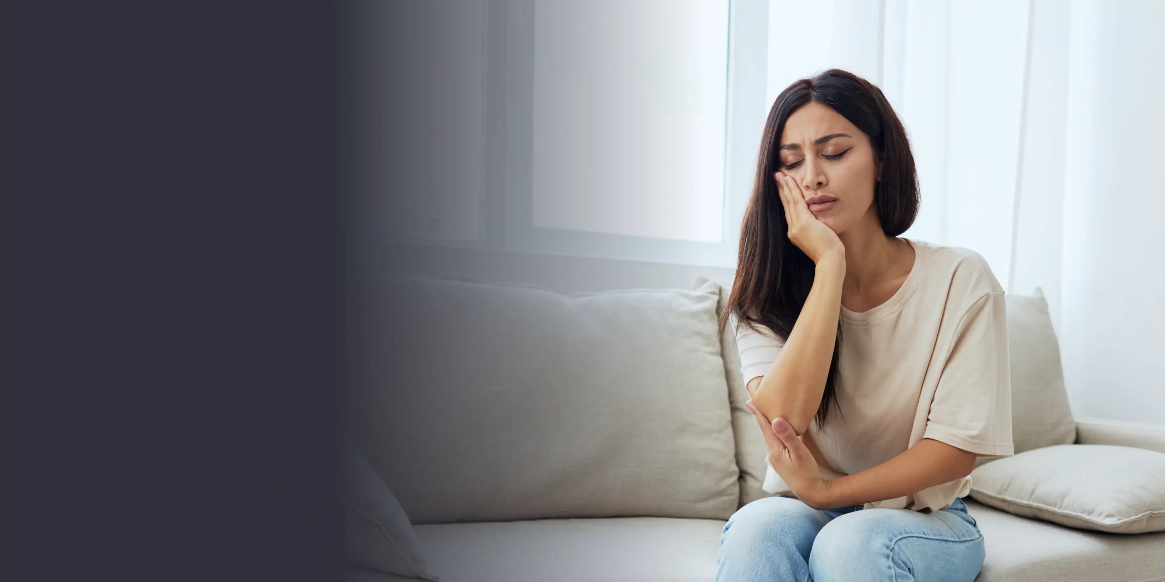 A woman sitting on a couch with her hand on her chin.