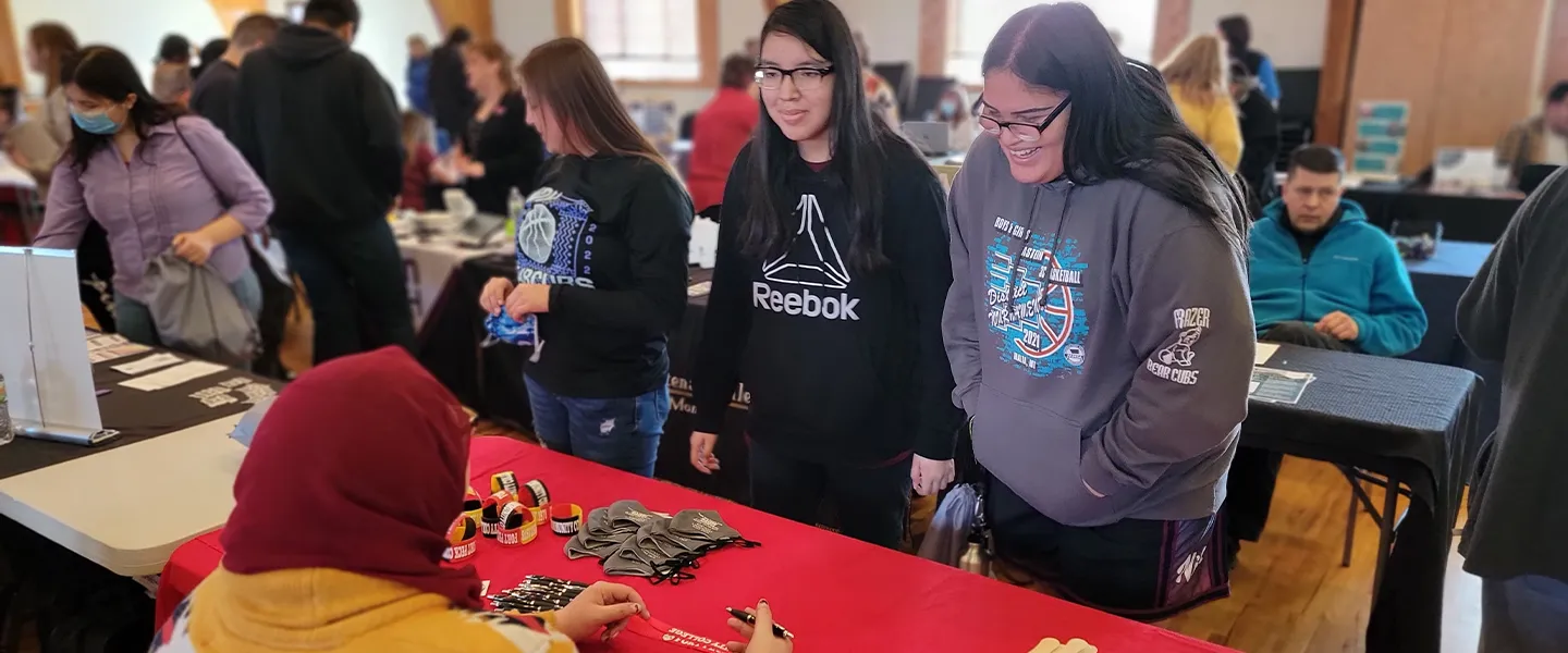 Fort Peck Community College students interacting with a vendor at a community event, showcasing engagement, cultural pride, and local partnerships.