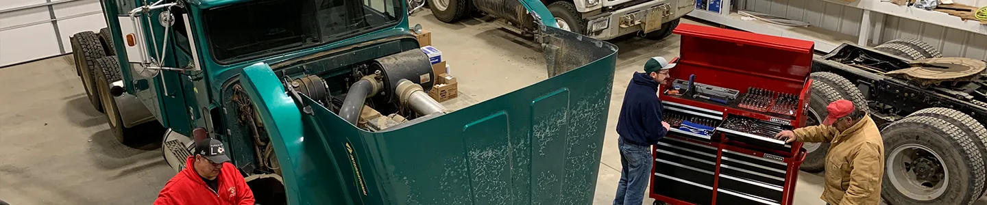 FPCC students and instructor working in a diesel mechanics lab with large trucks and tool cabinets, showcasing vocational training.