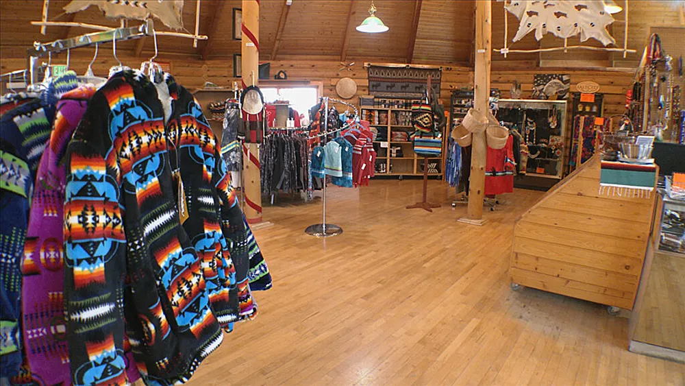 Interior of FPCC’s Titoka Tibi Bookstore featuring colorful Native American apparel, arts, crafts, star quilts, Pendleton products, and FPCC-branded merchandise in a warm wooden setting.