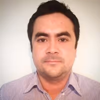 Hombre con cabello oscuro corto y camisa de rayas moradas, mirando a la cámara con fondo claro.