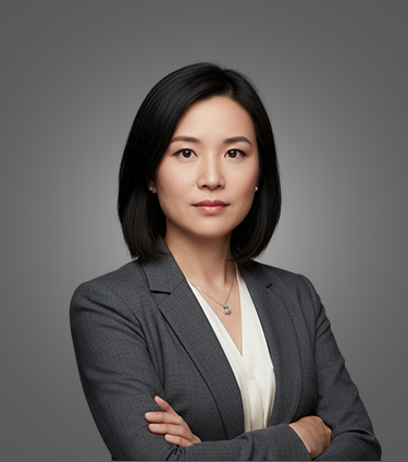 Confident woman with shoulder-length black hair wearing a gray blazer and white blouse on a gray background.
