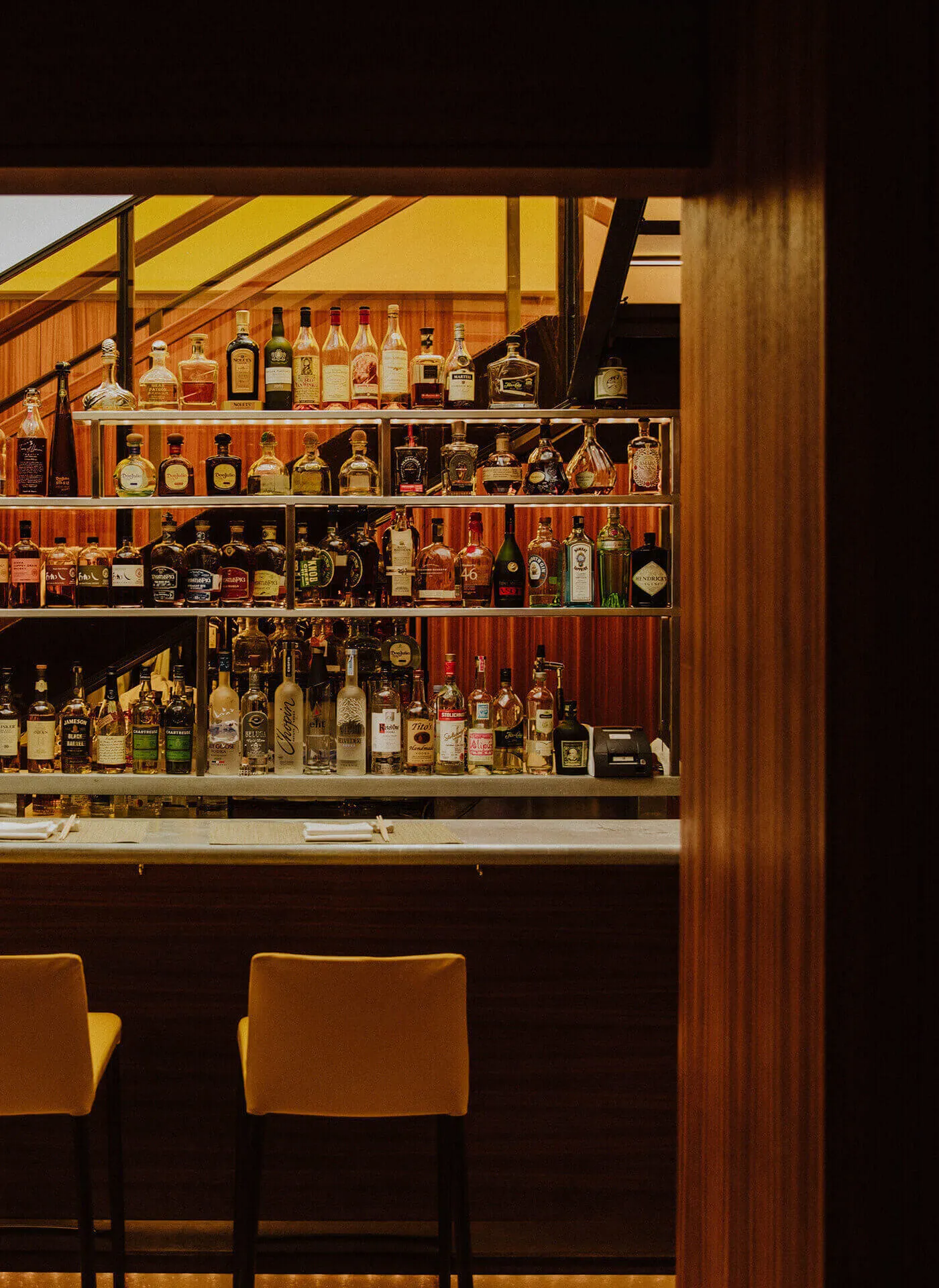 View of the bar and seating through a wooden archway, with staircase in the background.