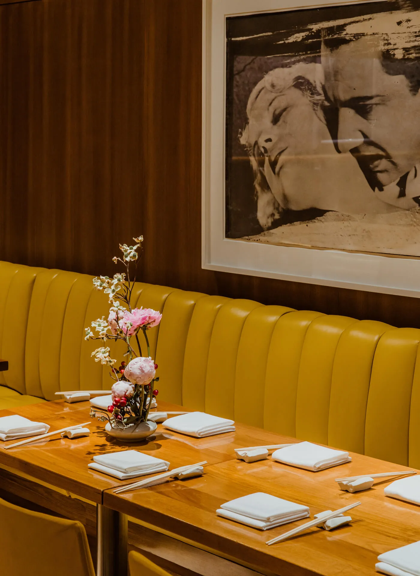 Table setting at the restaurant featuring a flower arrangement. Artwork from the Gagosian Gallery hanging on the wall.