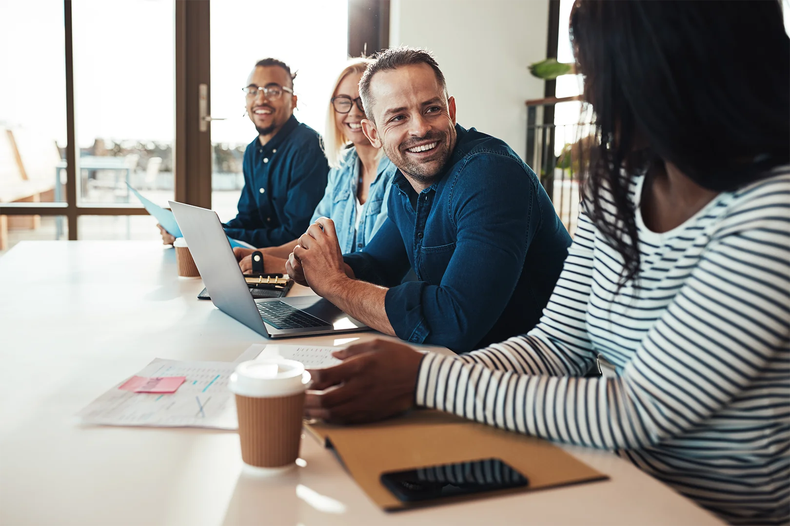 Group of people talking and laughing around a conference table