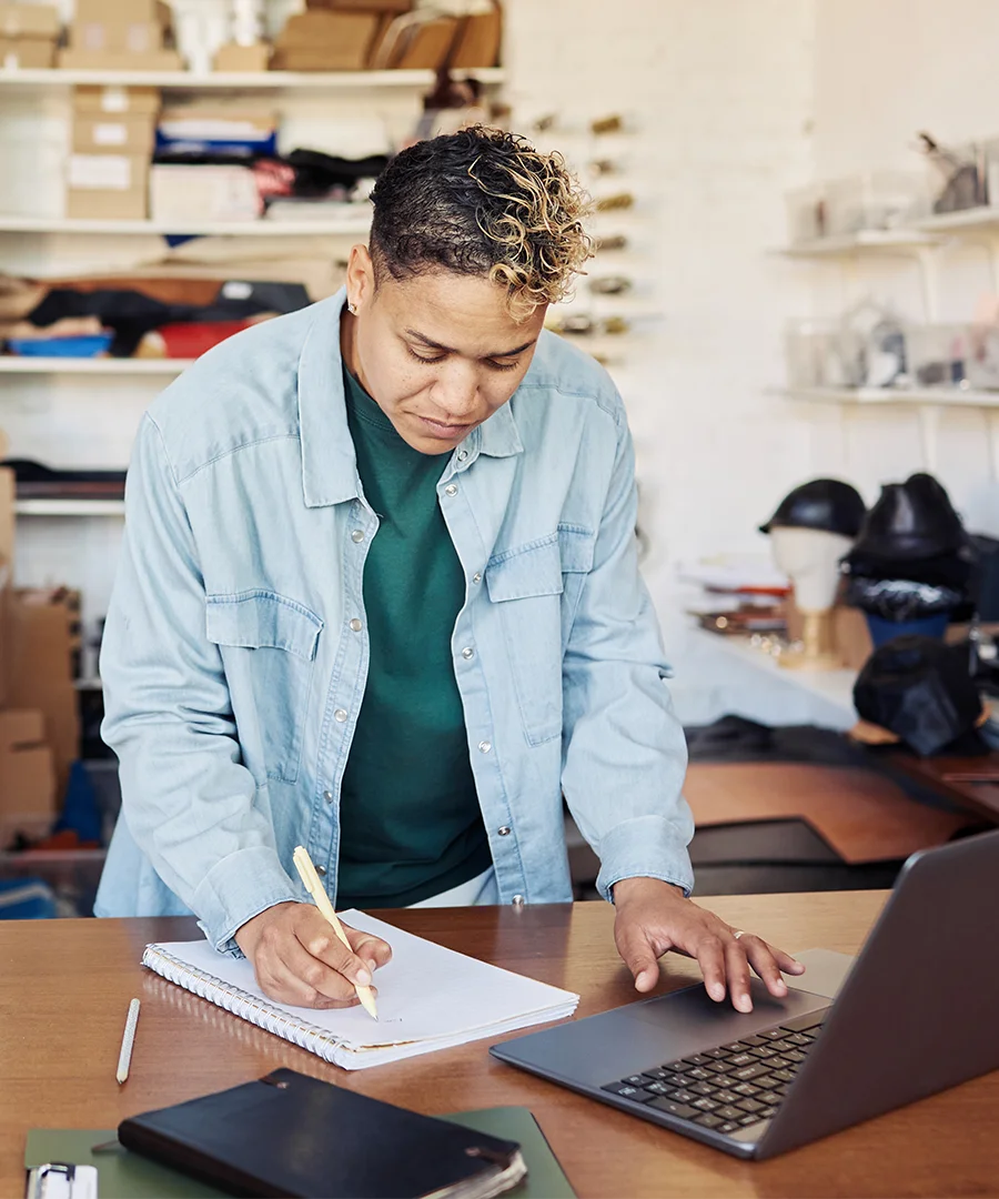 Woman using a computer and writing on a note pad