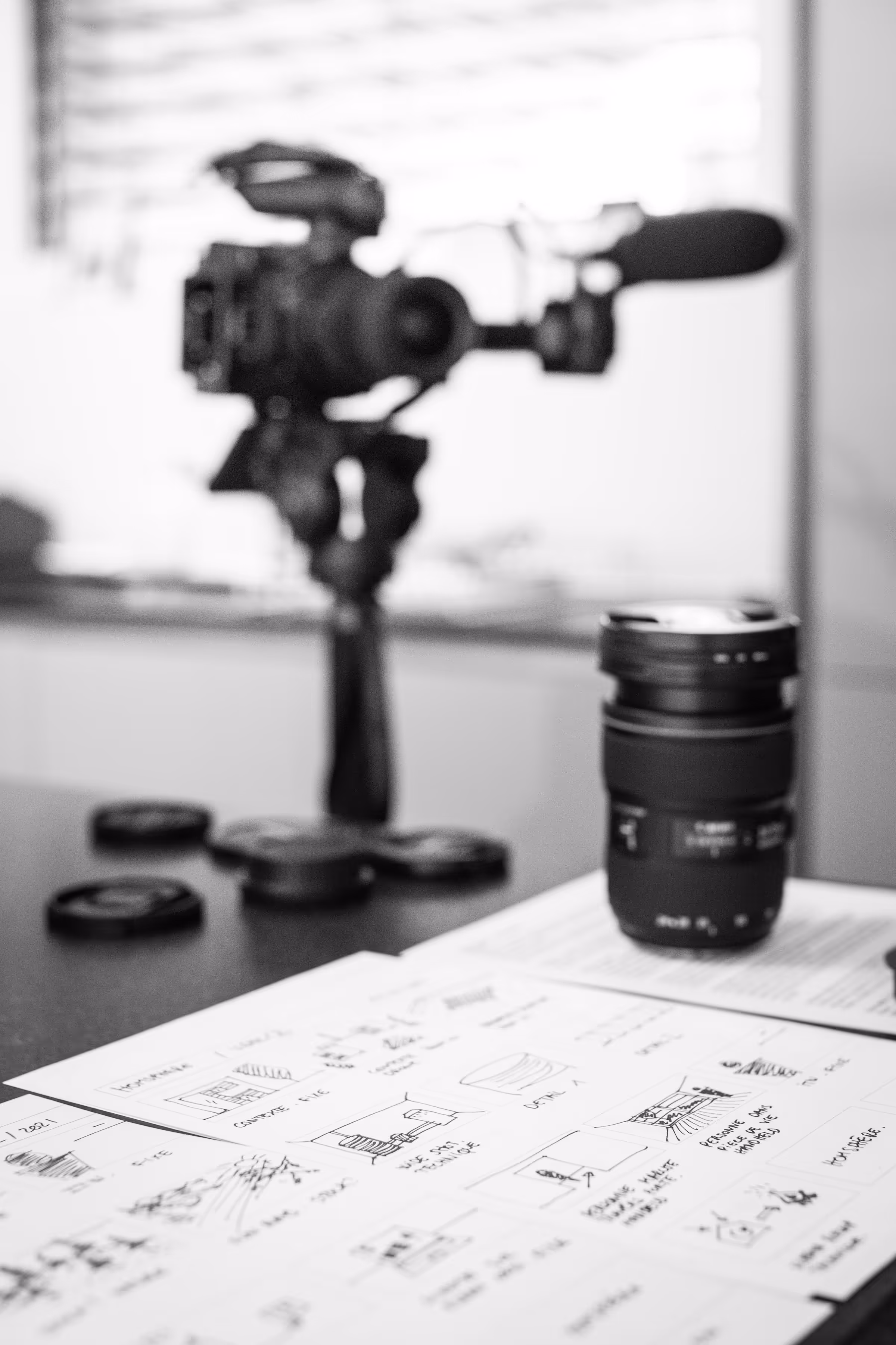 Professional camera setup and lens on a desk with film storyboards — behind the scenes of a wedding video editor crafting cinematic stories.