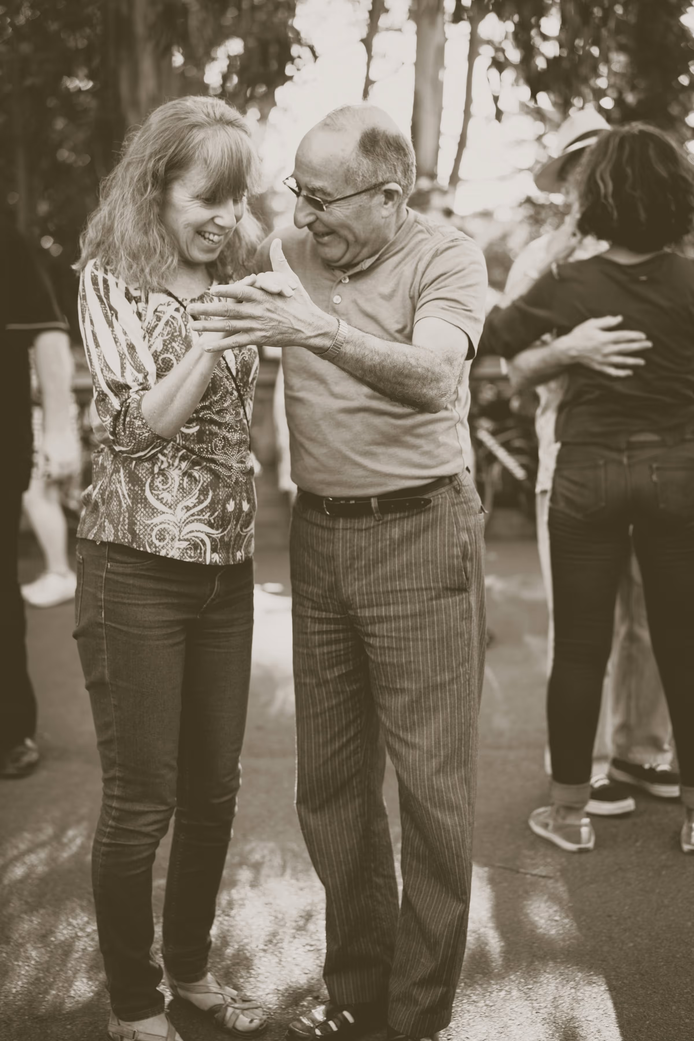Elderly couple smiling and dancing together outdoors at a wedding reception, captured in warm cinematic tones that highlight genuine emotion and timeless love.