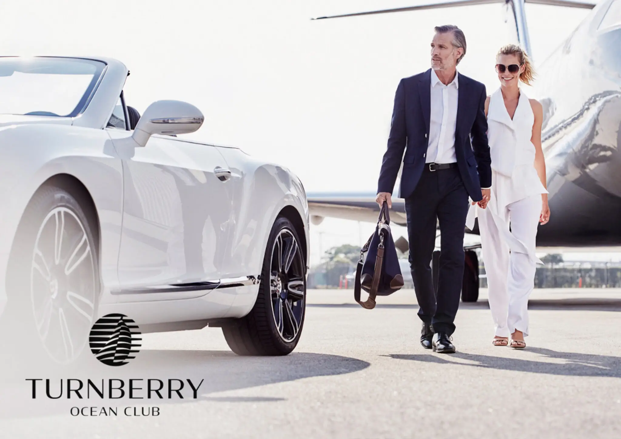 Well-dressed man and woman walking hand in hand near a private jet and a white luxury convertible car.