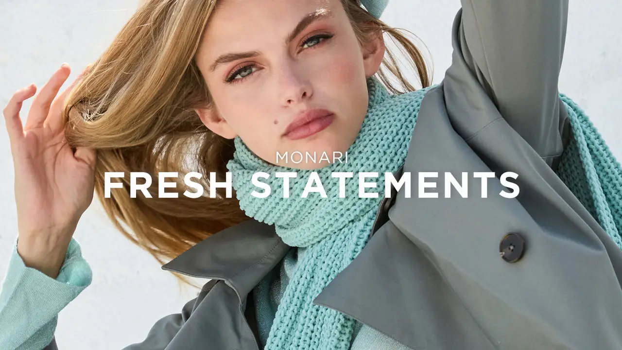 Close-up of a woman with flowing blonde hair wearing a mint green scarf and gray coat, with text reading 'Monari Fresh Statements.'