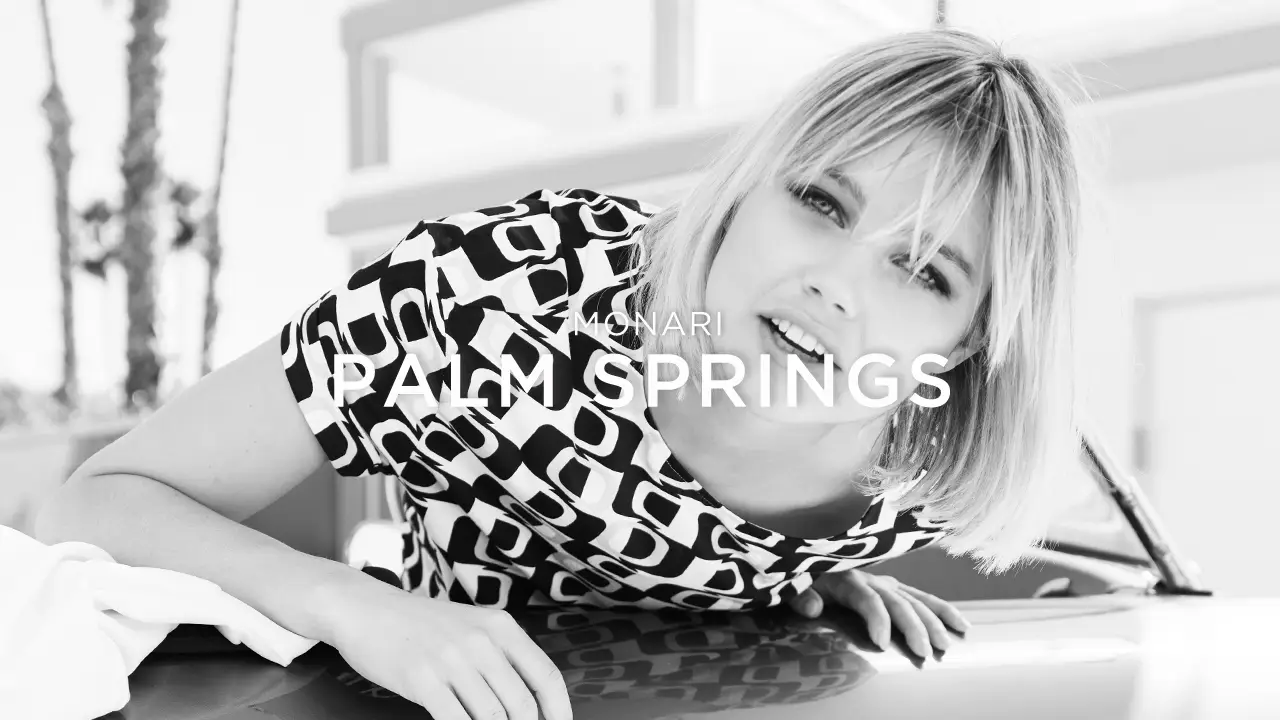Black and white photo of a woman leaning on a car hood wearing a patterned shirt, with text overlay 'MONARI PALM SPRINGS'.