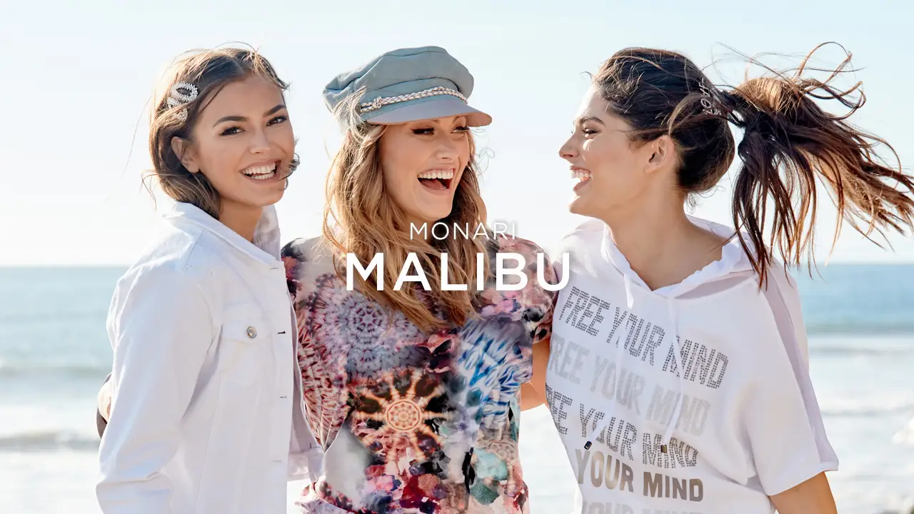 Three smiling women standing together by the beach, with the text 'Monari Malibu' overlayed.
