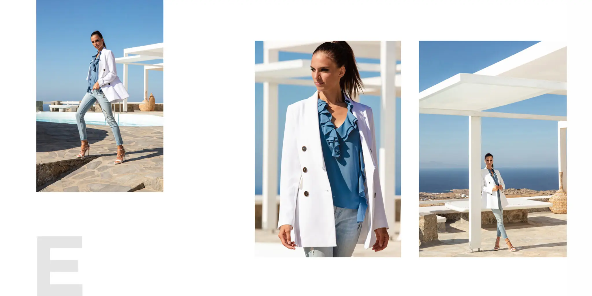 Woman wearing a white blazer, blue ruffled blouse, and light jeans posing outdoors with a blue sky and ocean in the background.