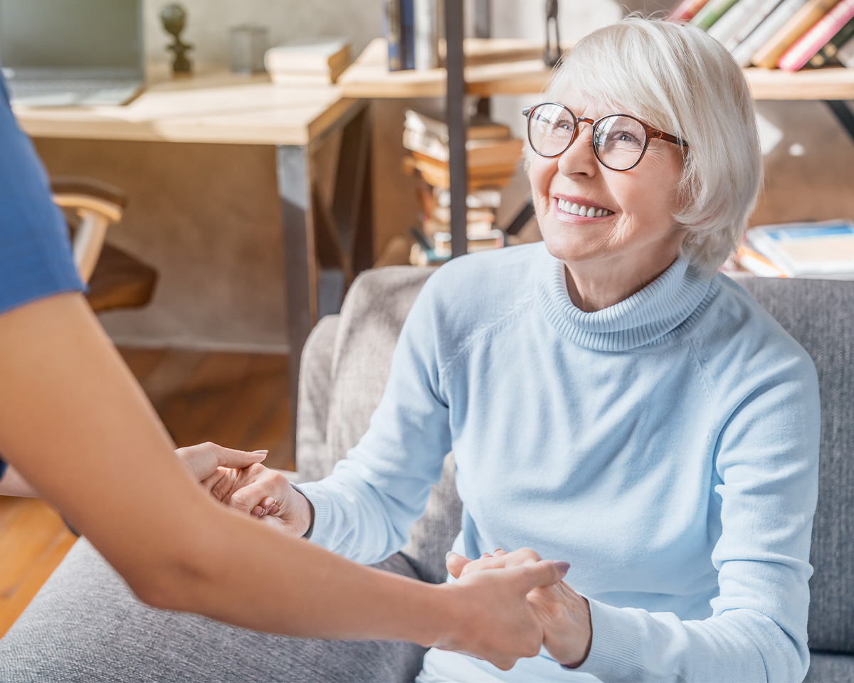 Seniorin hält die Hand Ihres Pflegehelfers
