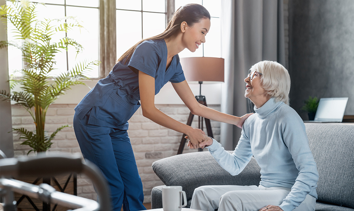 Alltagshilfe spricht mit einer Seniorin.