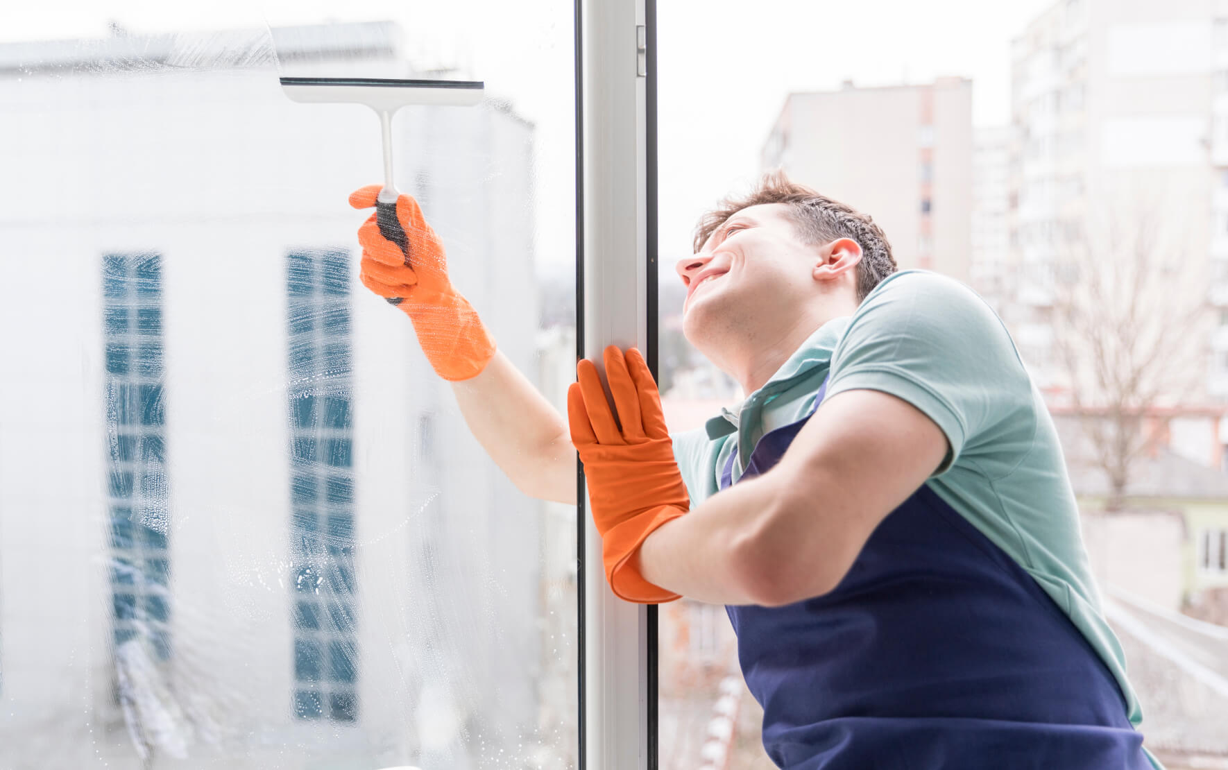 A man cleaning a window with an orange glove.